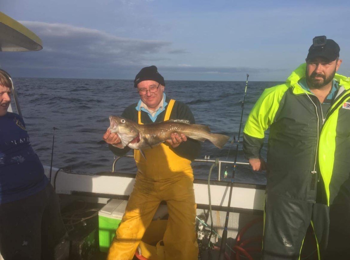Coach Kev Martin catching cod from a boat.